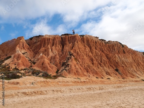 Red high cliffs at Praia da Falesia, a paradise beach in Albufeira in Portugal with a couple kissing