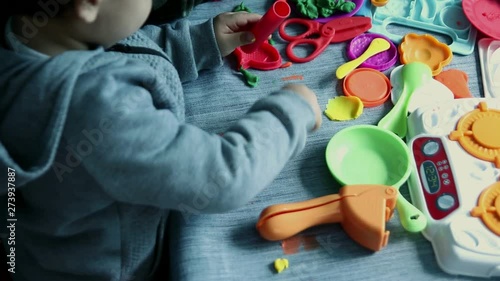 Child playing with pasticine dough and asorted acessories photo