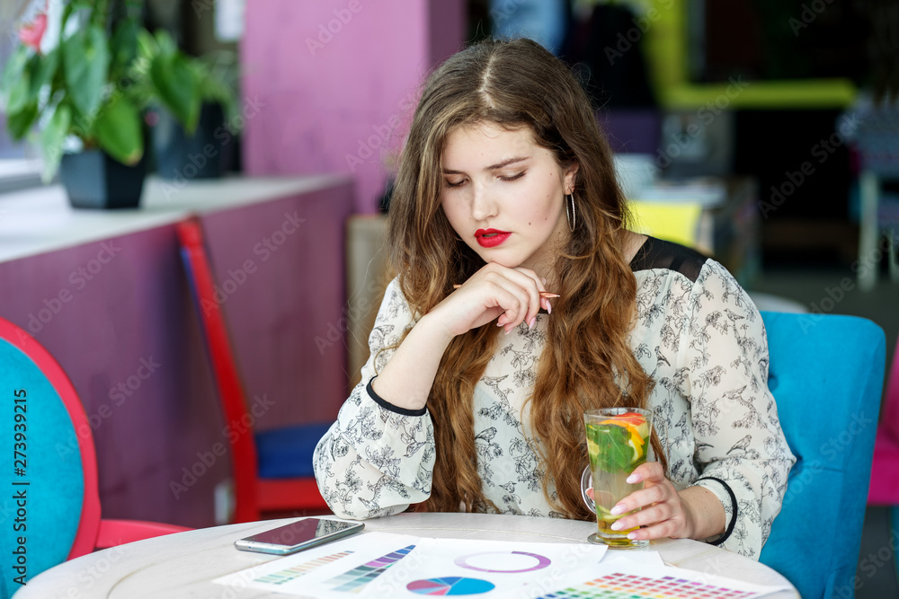 Fototapeta premium Smart serious girl student thinks about the project. Citrus tea with mint. The concept of work, business, education, freelance, lifestyle