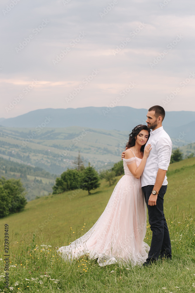 Beautiful young wedding couple standing on the green slope, hill. Groom and bride in Carpathian mountains