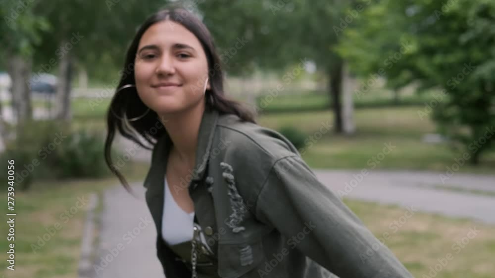 Cheerful hipster girl goes and dances in the park to the music while holding a portable speaker in her hand. Close-up Cheerful hipster girl goes and dances in the park to the music while holding a portable speaker in her hand. Close-up