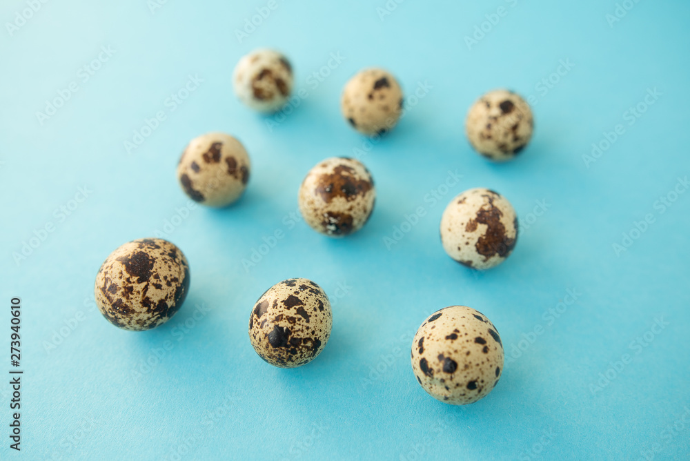 Raw quail eggs against blue background. Easter.