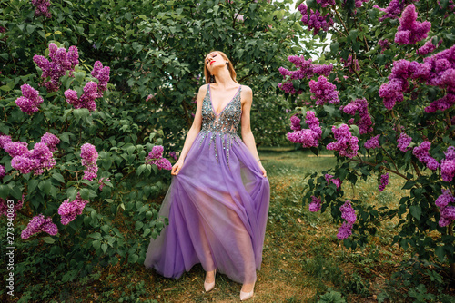 beautiful young happy girl in an incredible dress resting outdoors,woman walking in the park amid blooming lilacs