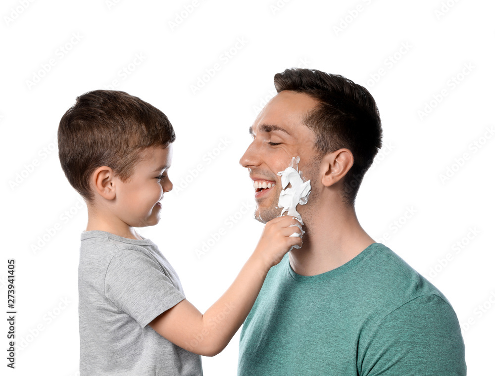 Little son applying shaving foam onto dad's face against white background Little son applying shaving foam onto dad's face against white background