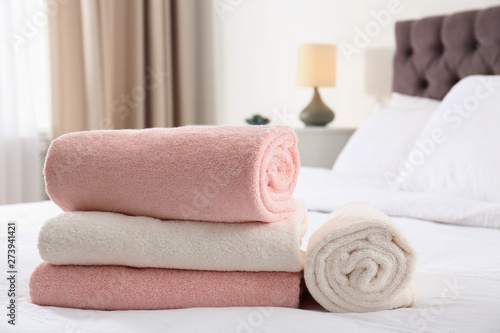 Folded and rolled soft towels on bed in room. Space for text