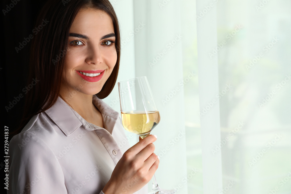 Beautiful young woman with glass of luxury white wine indoors. Space for text Beautiful young woman with glass of luxury white wine indoors. Space for text