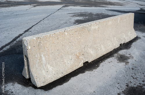 Concrete barrier on dirty asphalt.