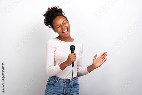 Funny woman singer holds a microphone in her hands against a ligth studio background photo