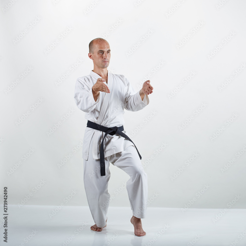 On the white surface professional adult athlete trains formal karate exercises On the white surface professional adult athlete trains formal karate exercises