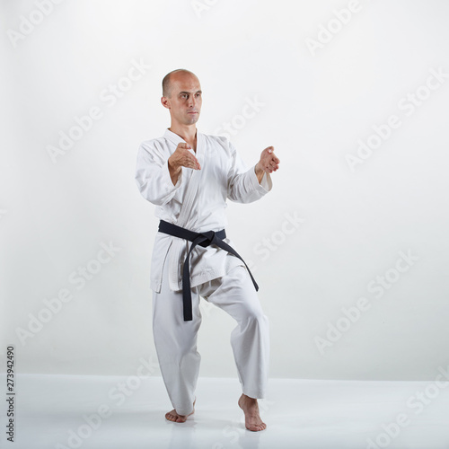 On the white surface professional adult athlete trains formal karate exercises