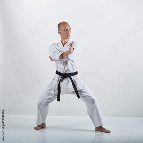 On a white surface, a professional athlete does formal karate exercises