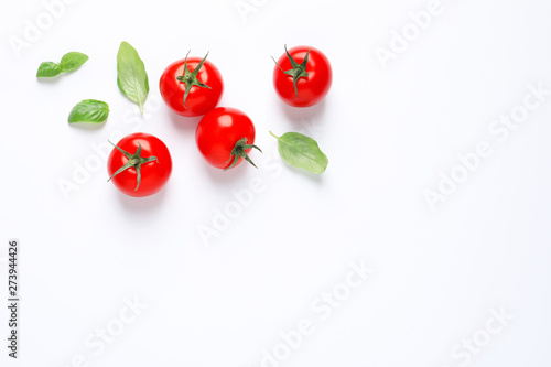 Fototapeta Naklejka Na Ścianę i Meble -  Composition with ripe cherry tomatoes and basil leaves on white background, top view