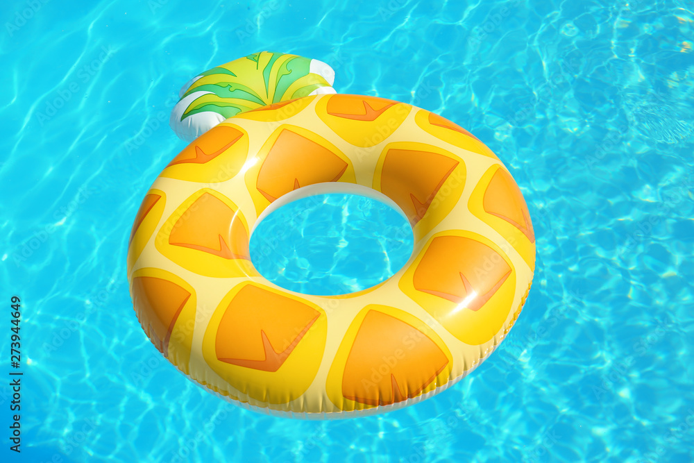Bright inflatable pineapple ring floating in swimming pool on sunny day