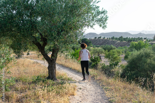 Fit middle-aged woman running through a rural field © Cristian Blázquez