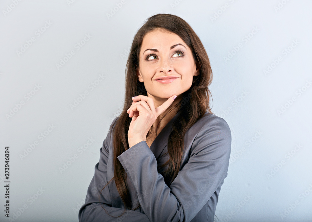 Beautiful success business woman in suit with finger under the face thinking and looking up on blue background. Closeup Beautiful success business woman in suit with finger under the face thinking and looking up on blue background. Closeup