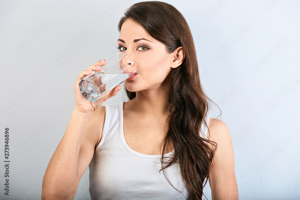 Positive happy smiling woman with healthy skin and long curly hair drinking pure water and looking. Closeup Positive happy smiling woman with healthy skin and long curly hair drinking pure water and looking. Closeup
