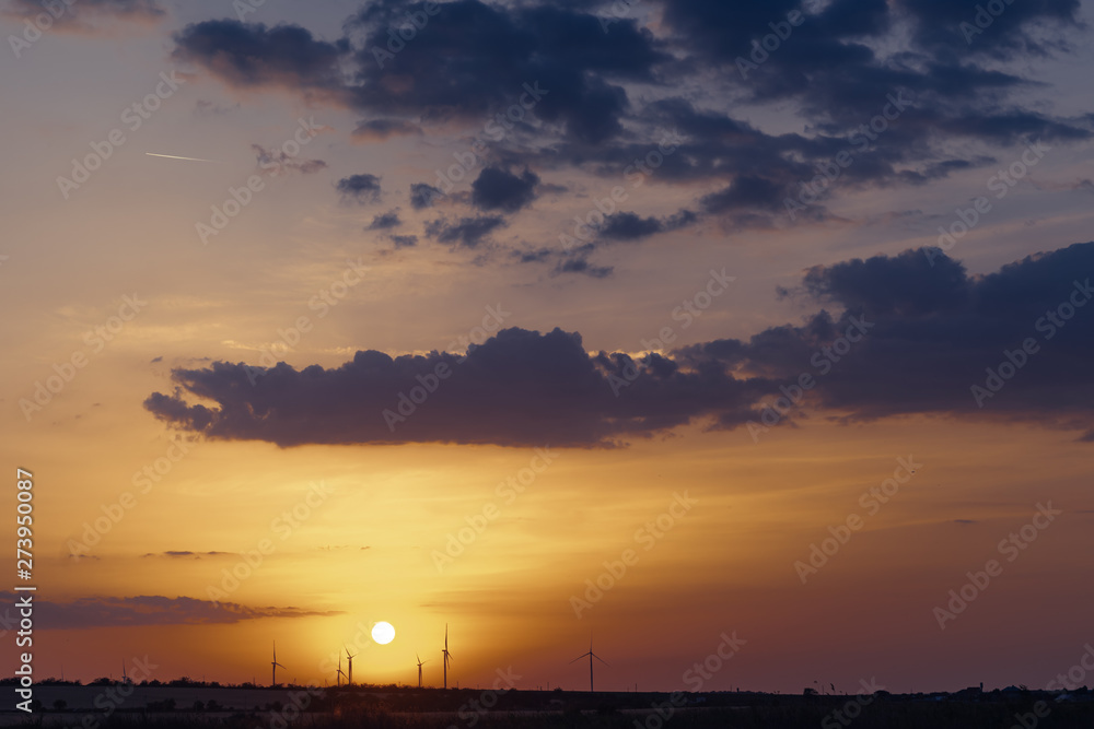 Wind power generators on the horizon against the backdrop of a beautiful sunset.