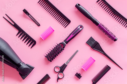 Fototapeta Naklejka Na Ścianę i Meble -  Combs, dryer, sciccors and hairdresser tools in beauty salon work desk on pink background top view pattern