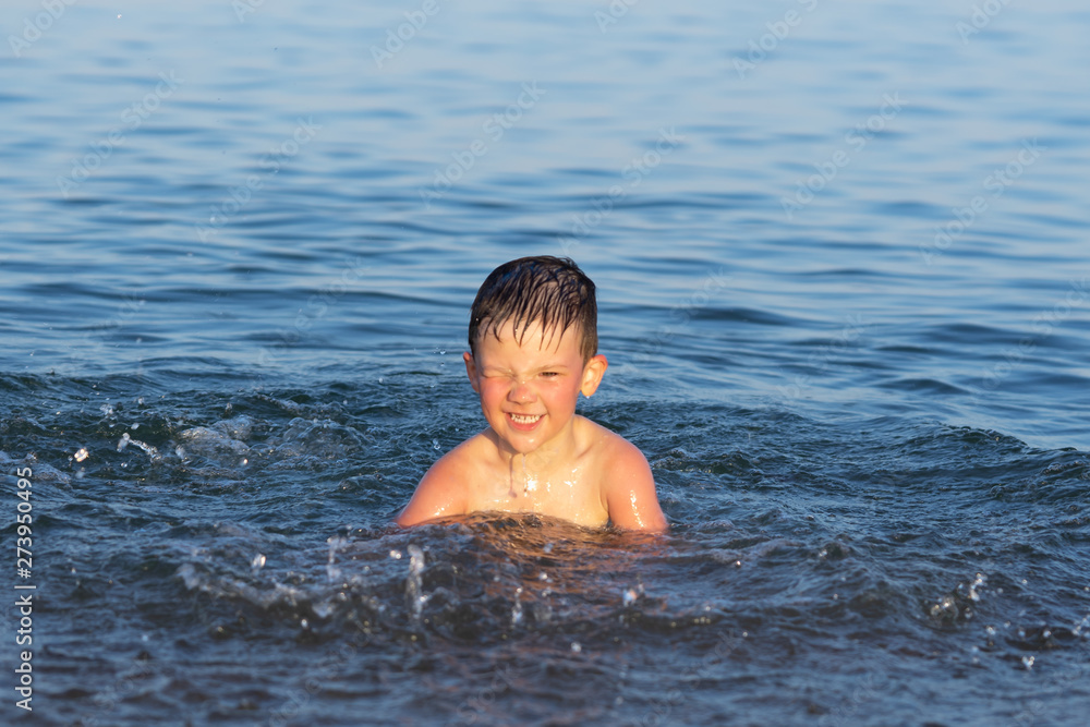 A boy of three years is swimming in the sea at sunset with his brother. A boy of three years is swimming in the sea at sunset with his brother.