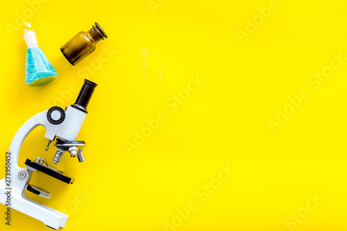 Do medical research with microscope, test-tubes in lab on yellow background top view mock-up