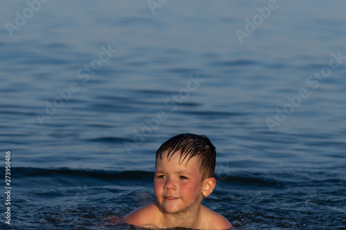 A boy of three years is swimming in the sea at sunset with his brother. © Виктор Кеталь