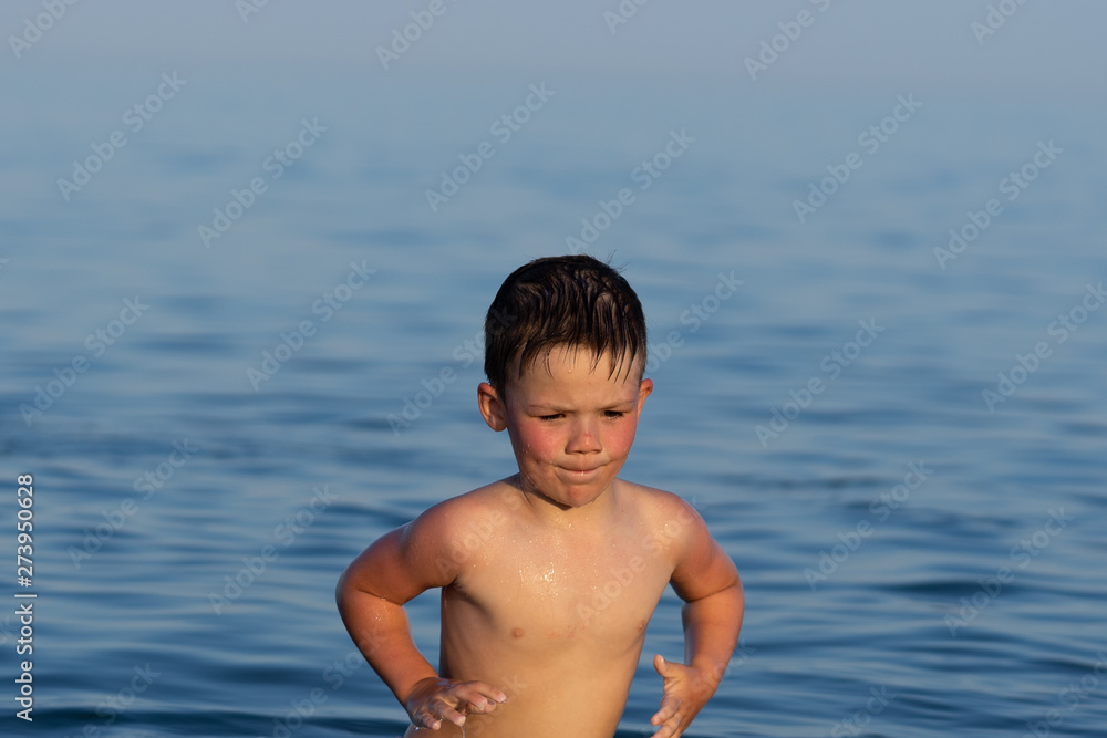 A boy of three years is swimming in the sea at sunset with his brother.