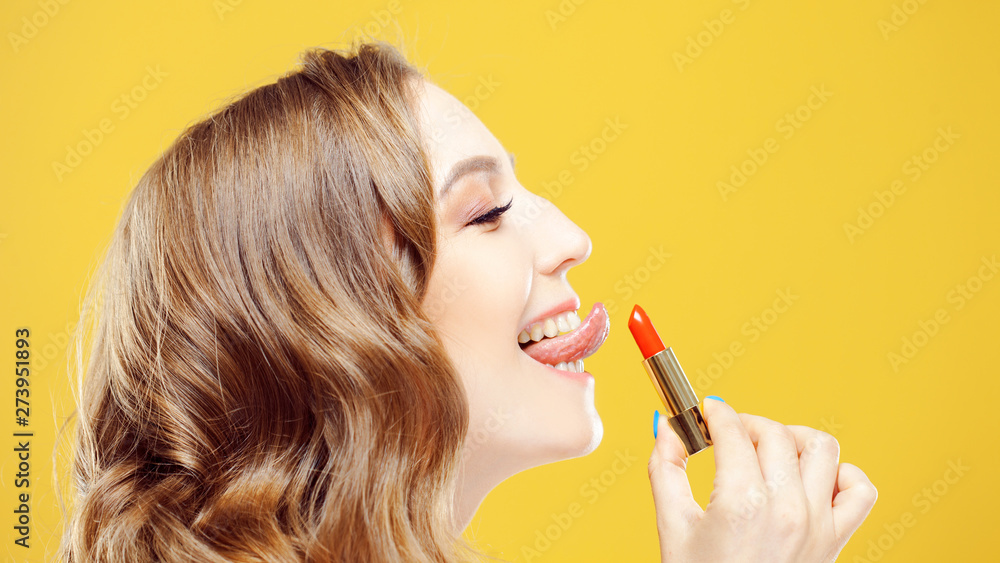 Obraz premium Sexy girl licked her tongue lipstick. Funny portrait of young beautiful woman with lipstick
