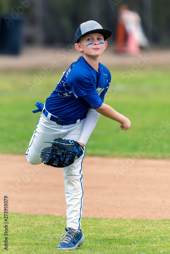 Photography Youth baseball player in blue uniform following through on throw made in the infield during a game