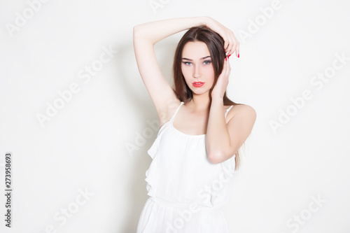 woman in white dress holds hands around her head