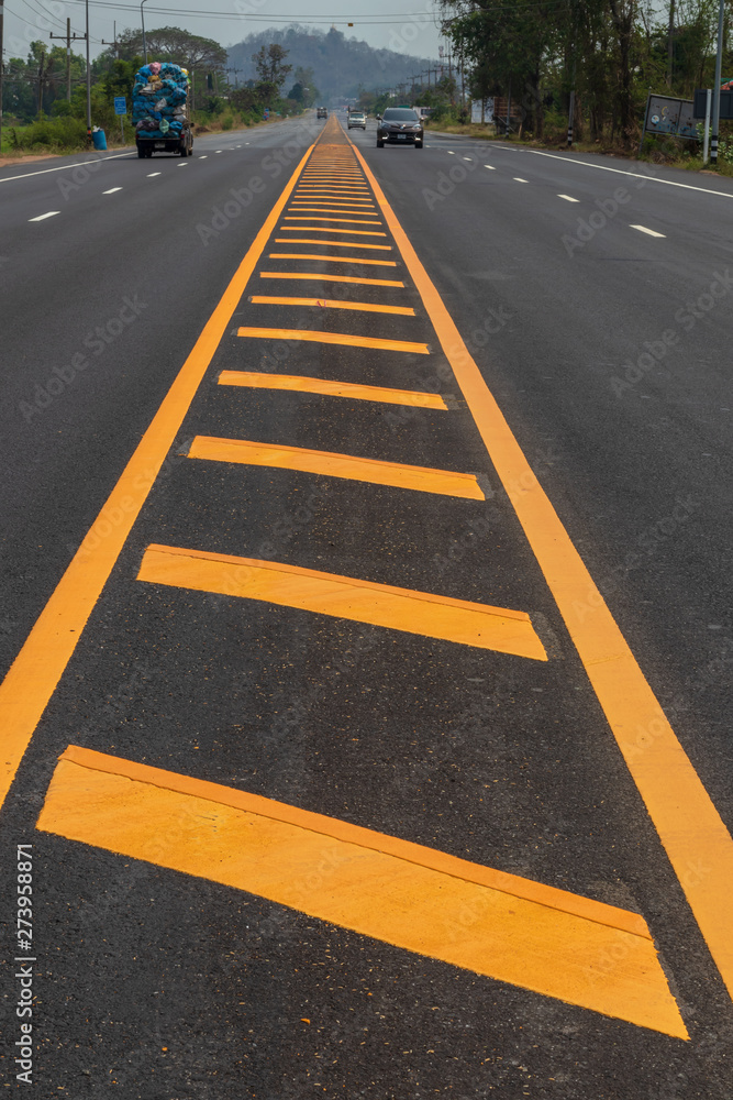 Yellow lines on the paved road with mountains.