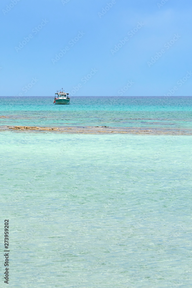 Turquoise blue sea water on a lagoon with a ship on a horizon line ander a cloudy sky. Copy space. Turquoise blue sea water on a lagoon with a ship on a horizon line ander a cloudy sky. Copy space.