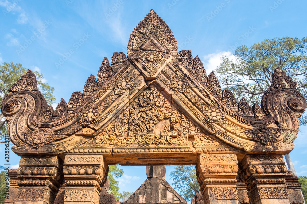 Obraz premium The beautiful details of sandstone Bas-reliefs in Banteay Srei a 10th-century Cambodian temple dedicated to the Hindu god Shiva made by pink/red sandstone in Siem Reap, Cambodia.