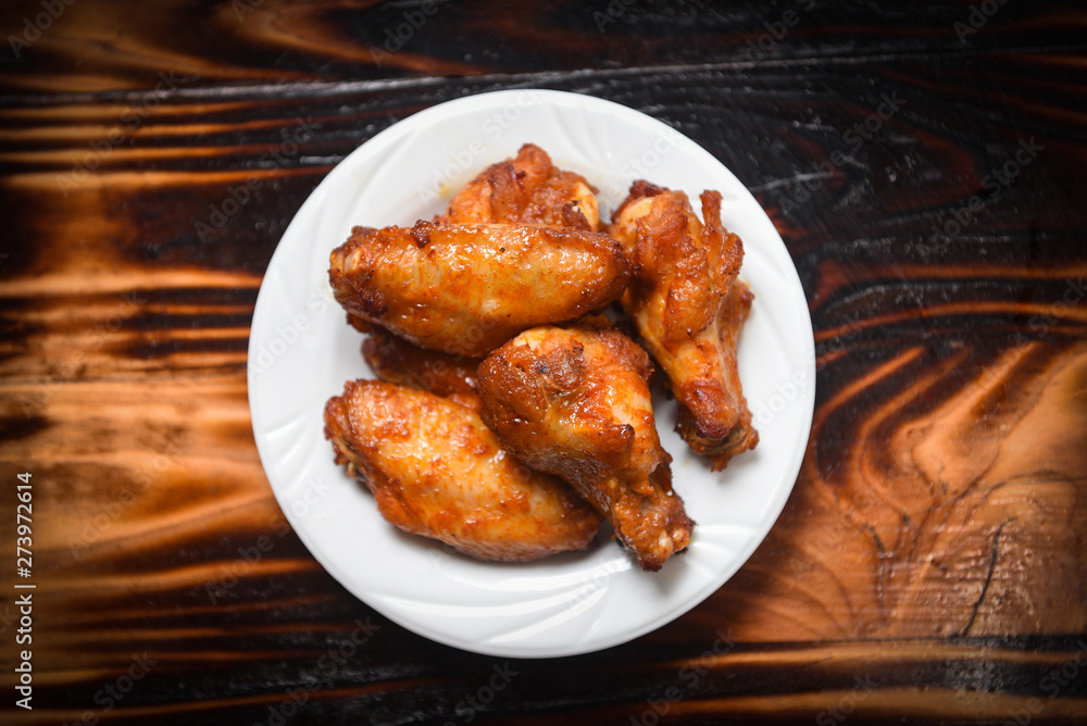 Baked chicken wing bbq grill on plate / hot and spicy chicken on dark background Baked chicken wing bbq grill on plate / hot and spicy chicken on dark background