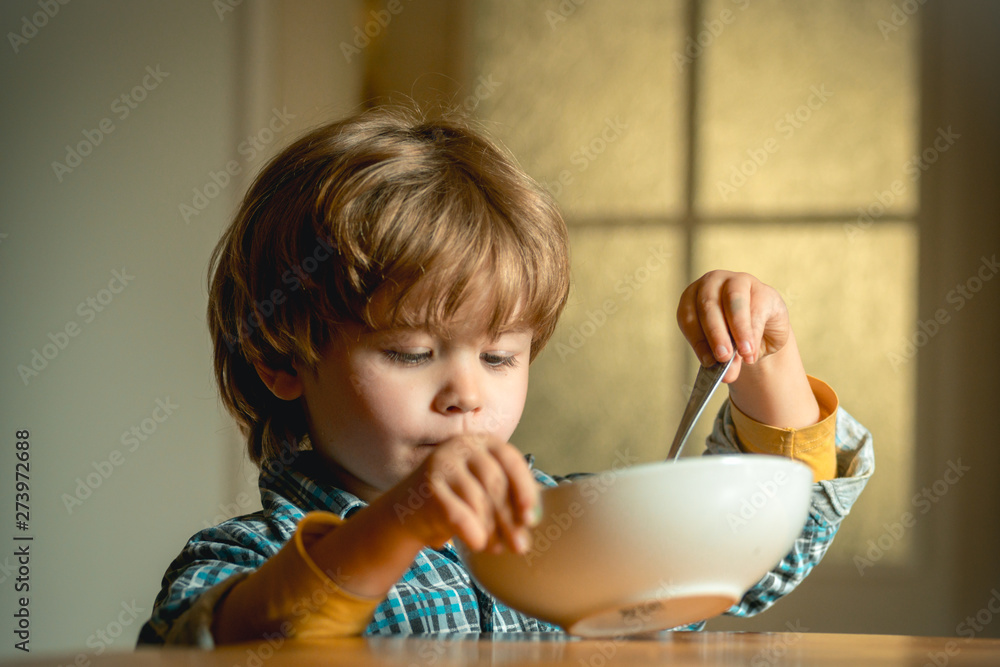 Kid eating. Little boy having breakfast in the kitchen. Cute child eating breakfast at home. Baby eating.