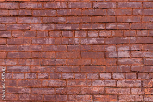 Old red painted brick wall with beautiful rows of speckled bricks.