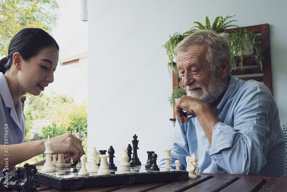 senior man happiness and nurse, playing chess at balcony near garden at nursing home together senior man happiness and nurse, playing chess at balcony near garden at nursing home together