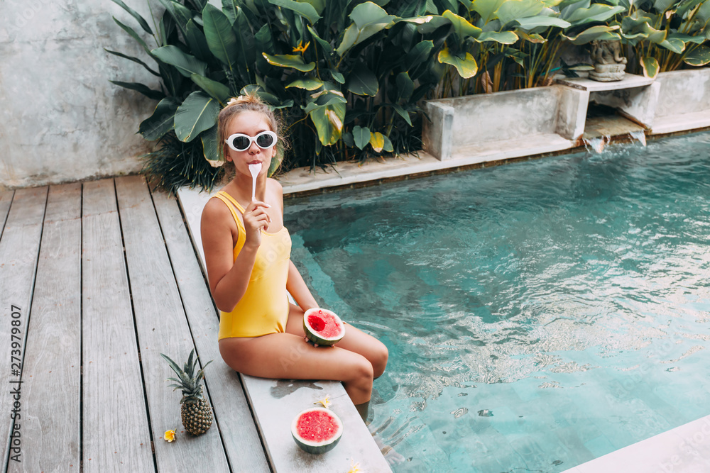 Girl eating watermelon in pool on luxury villa in Bali - obrazy, fototapety, plakaty 