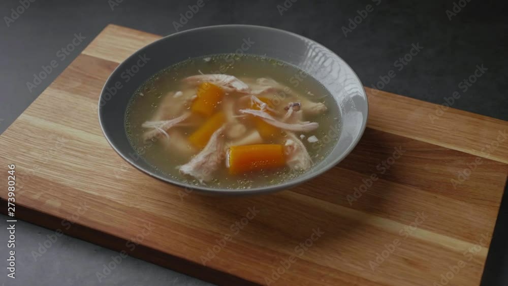 Serving fresh hot healthy paleo chicken broth soup to wooden board on concrete background. Serving fresh hot healthy paleo chicken broth soup to wooden board on concrete background.