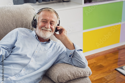 senior man happiness sitting on the sofa and listening music with headphone at living room for relaxing