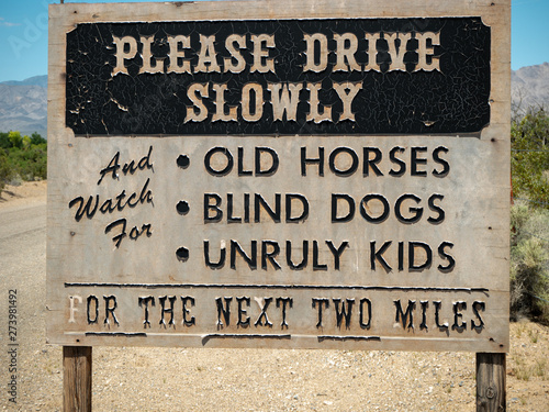 A drive slowly road sign cautioning about old horses, blind dogs, and unruly children 