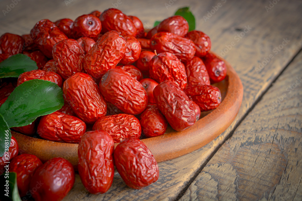 China xinjiang red date with green leaves on wooden plate for soup making purposes. China xinjiang red date with green leaves on wooden plate for soup making purposes.