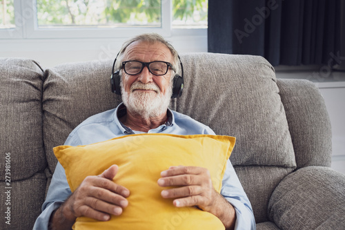 senior man happiness sitting on the sofa and listening music with headphone at living room for relaxing