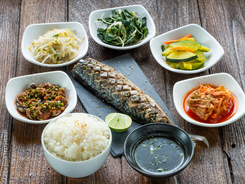 One set of saba grill serve with slide dish, kimchi, rice and seaweed soup with korean style serve menu on wood table.