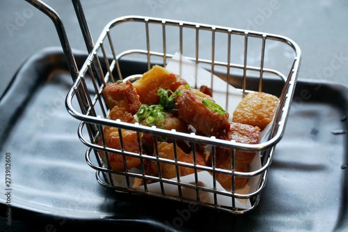 Soft focus of fried pork in the Iron basket on black plate in restaurant, copy space, ready to eat or serve, Selective focus (Tamanegi Kurobuta), on dark background photo