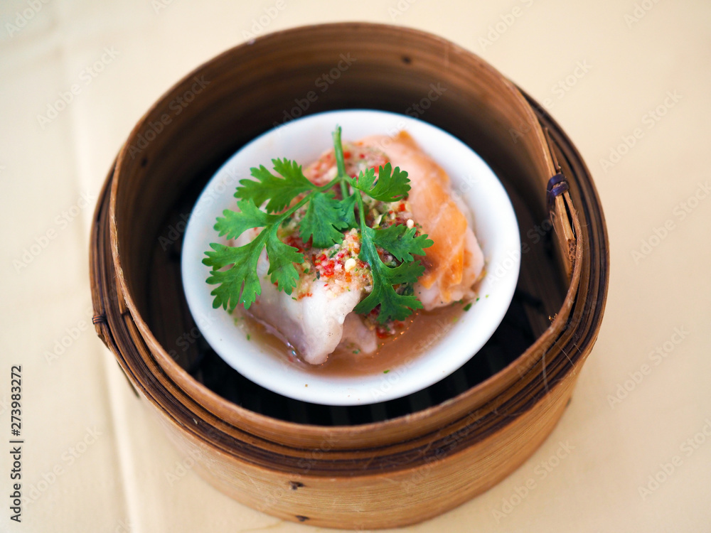 A bamboo basket of steamed salmon with spicy and sour sauce. kind of yum cha or dimsum Chinese traditional food style with selective focus. A bamboo basket of steamed salmon with spicy and sour sauce. kind of yum cha or dimsum Chinese traditional food style with selective focus.