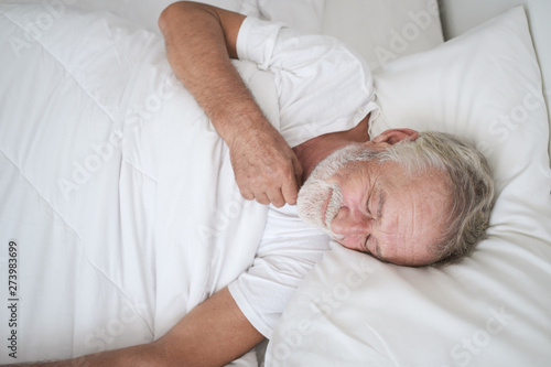 senior man sleeping alone and headache or dreaming nightmare on bed in room