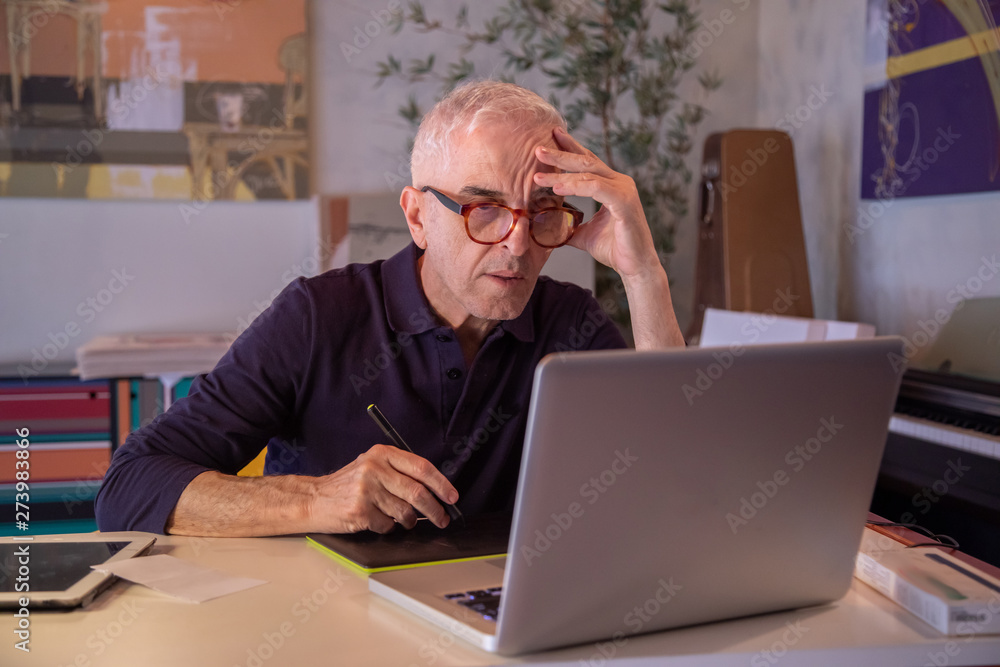 Middle aged man using computer in his art studio and drawing on his tablet Middle aged man using computer in his art studio and drawing on his tablet