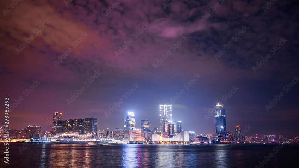 Hong Kong city’s skyline with Victoria Habour at night, shot from HK island side, with a colourful sky showing the lights pollution from skyscrapers.
