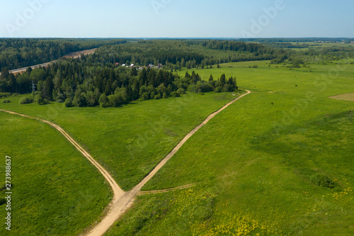 Aerial view of a country road through a field and forest