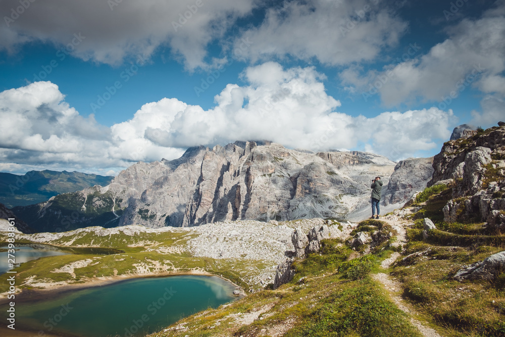 Beautiful landscape mountain view. Hiking path and mountain lake. Photographer on a rock. Tre come di lavaredo
